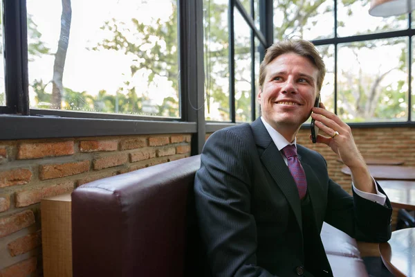 Feliz hombre de negocios reflexivo sonriendo y hablando por teléfono móvil — Foto de Stock