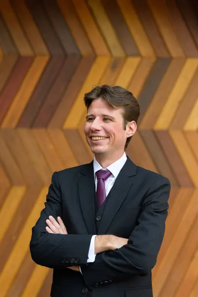 Feliz hombre de negocios sonriendo y pensando con los brazos cruzados contra — Foto de Stock