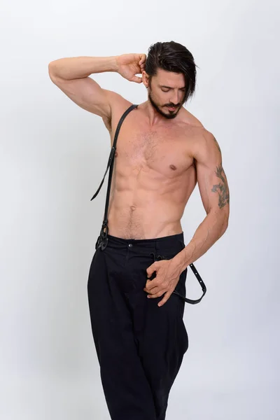 Plan studio d'un bel homme posant avec des bretelles torse nu — Photo