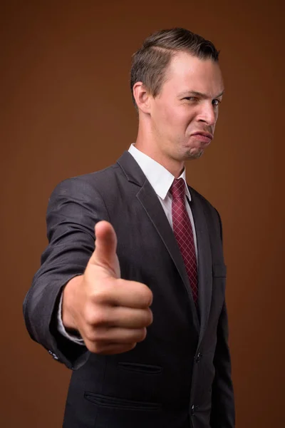 Studio shot of businessman against brown background — Stock Photo, Image