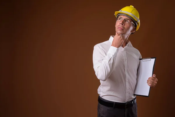 Porträtt av affärsman bära hardhat mot brun bakgrund — Stockfoto