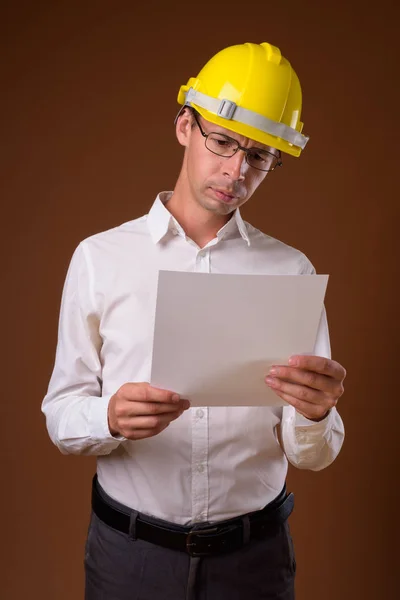 Porträtt av affärsman bära hardhat mot brun bakgrund — Stockfoto