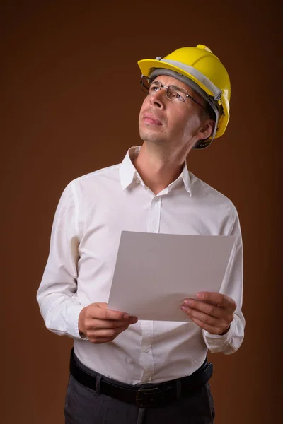 Porträtt av affärsman bära hardhat mot brun bakgrund — Stockfoto