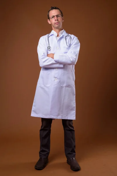 Studio shot of man doctor against brown background — Stock Photo, Image