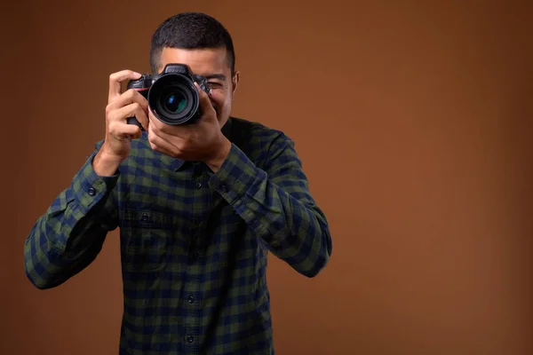 Joven hombre asiático multiétnico contra fondo marrón — Foto de Stock