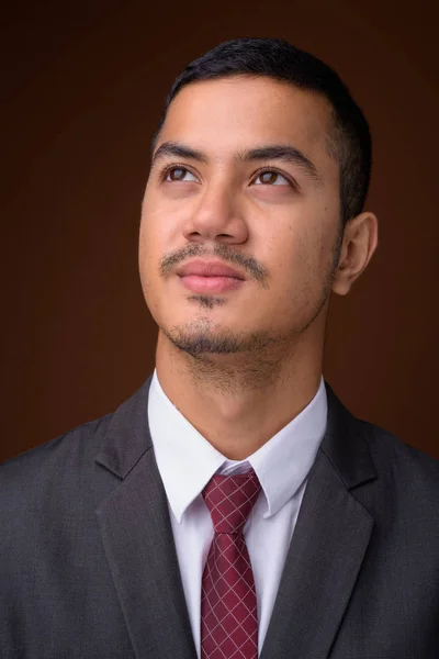 Young multi-ethnic Asian businessman against brown background — Stock Photo, Image