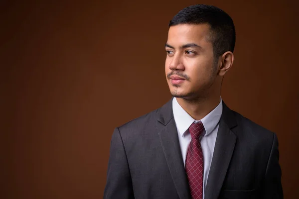 Joven empresario asiático multiétnico contra fondo marrón — Foto de Stock