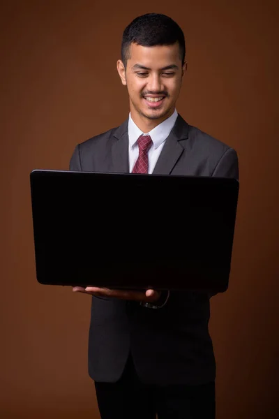 Joven empresario asiático multiétnico contra fondo marrón —  Fotos de Stock