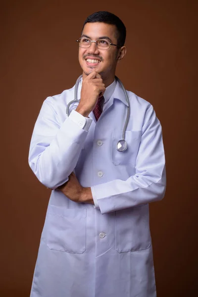 Mladík multietnické asijské doktor proti hnědým pozadím — Stock fotografie