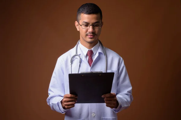 Jeune homme multi-ethnique asiatique médecin sur fond brun — Photo