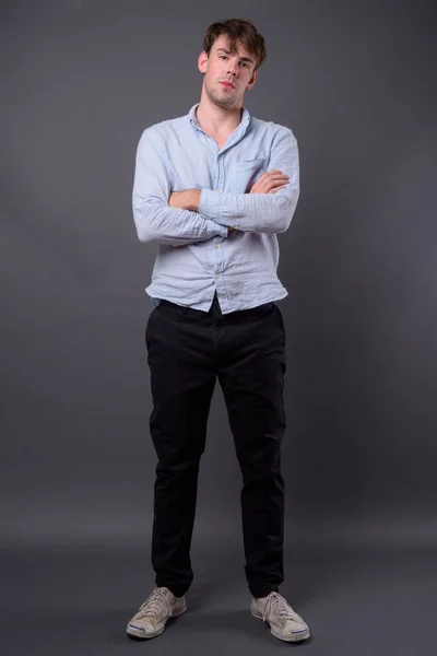 Studio shot of young handsome man against gray background — Stock Photo, Image