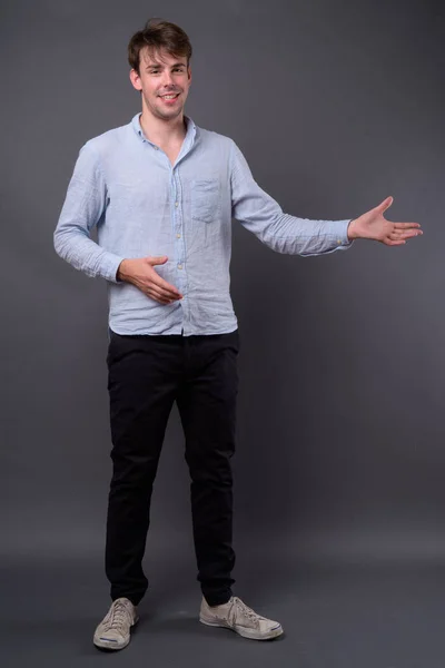 Studio shot of young handsome man against gray background — Stock Photo, Image