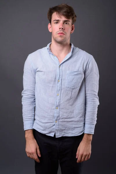 Studio shot of young handsome man against gray background — Stock Photo, Image