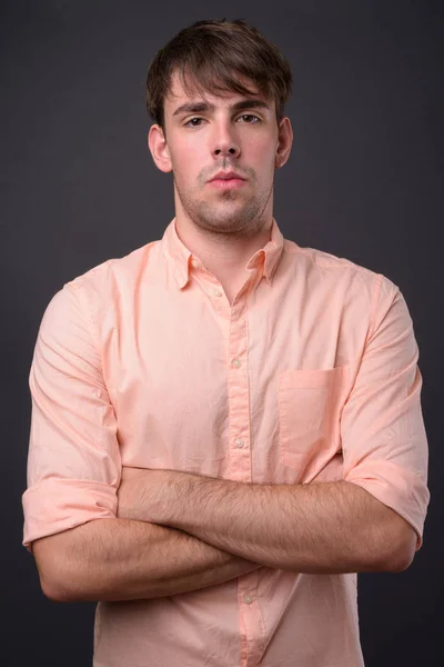 Portrait of young handsome businessman against gray background — Stock Photo, Image