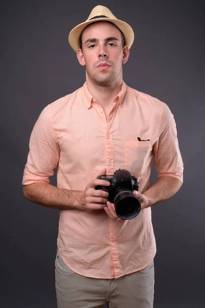 Joven hombre turista guapo sobre fondo gris —  Fotos de Stock