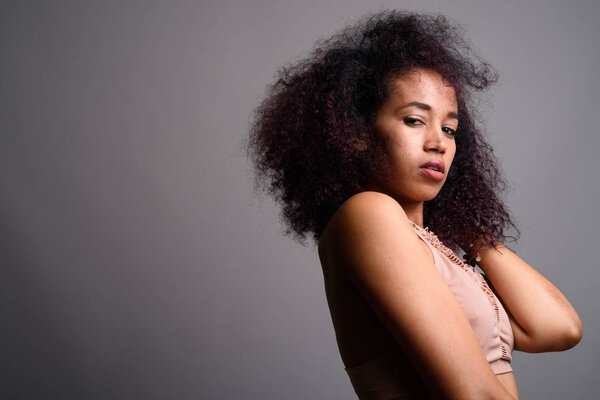 Young beautiful African woman against gray background