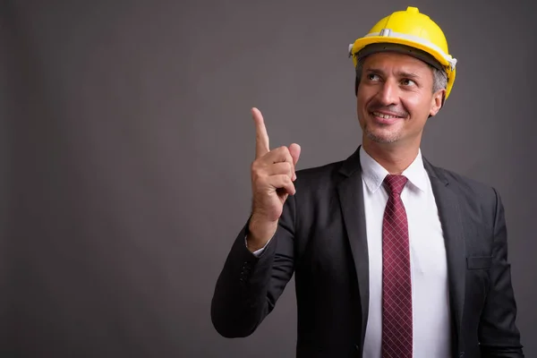 Porträtt av affärsman med hardhat mot grå bakgrund — Stockfoto