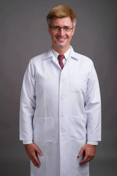 Hombre doctor con pelo rubio contra fondo gris — Foto de Stock