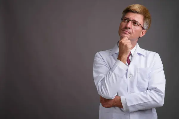 Hombre doctor con pelo rubio contra fondo gris — Foto de Stock