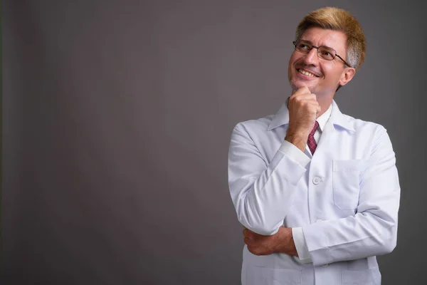 Hombre doctor con pelo rubio contra fondo gris — Foto de Stock