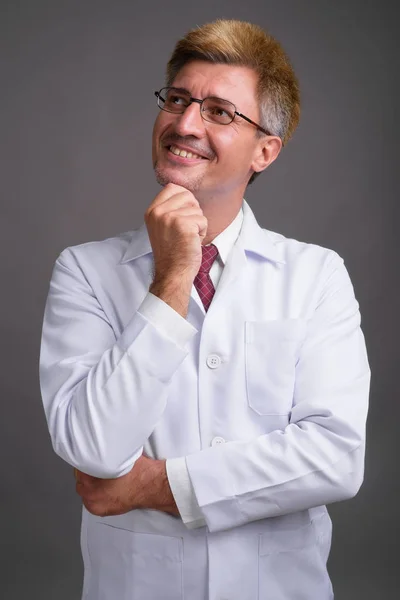 Doktor muž s blond vlasy proti šedé pozadí — Stock fotografie