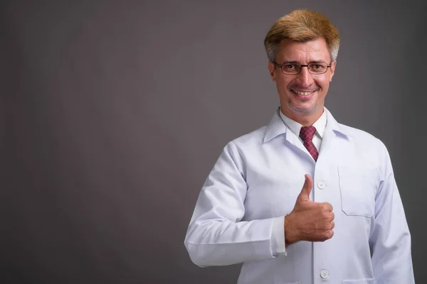 Hombre doctor con pelo rubio contra fondo gris — Foto de Stock