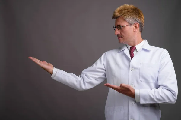 Lekarz mężczyzna z blond włosów szarym tle — Zdjęcie stockowe