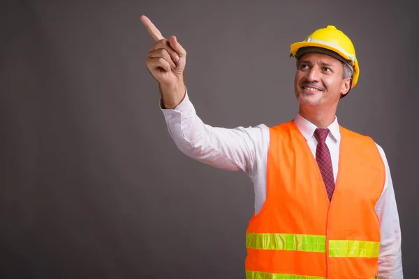 Portret van man bouwvakker tegen de grijze achtergrond — Stockfoto