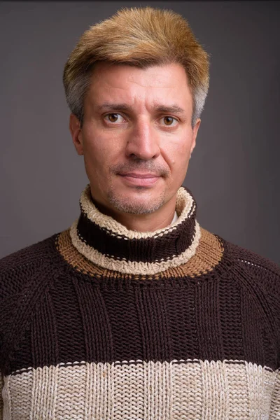 Homme aux cheveux blonds portant un pull col roulé contre le dos gris — Photo