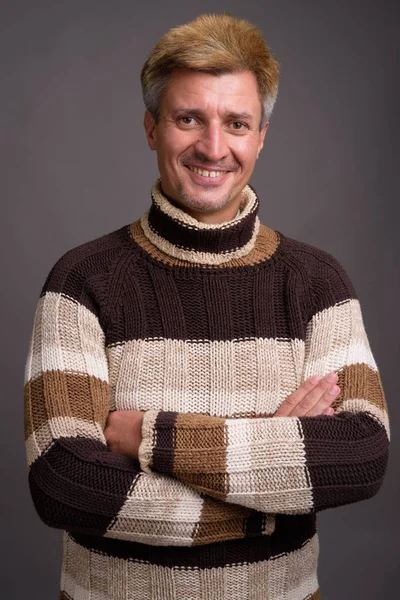 Uomo con i capelli biondi indossa maglione dolcevita contro la schiena grigia — Foto Stock