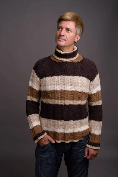 Uomo con i capelli biondi indossa maglione dolcevita contro la schiena grigia — Foto Stock