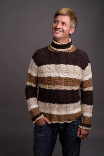 Man with blond hair wearing turtleneck sweater against gray back — Stock Photo, Image