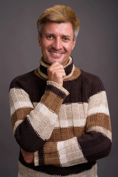Człowiek z blond włosami na sobie sweter z golfem przeciwko szary grzbiet — Zdjęcie stockowe