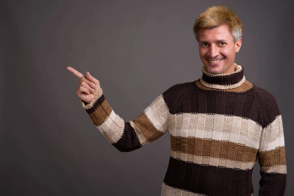 Man with blond hair wearing turtleneck sweater against gray back — Stock Photo, Image