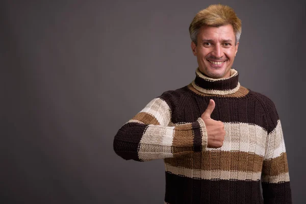 Pria berambut pirang mengenakan sweater turtleneck melawan punggung abu-abu — Stok Foto