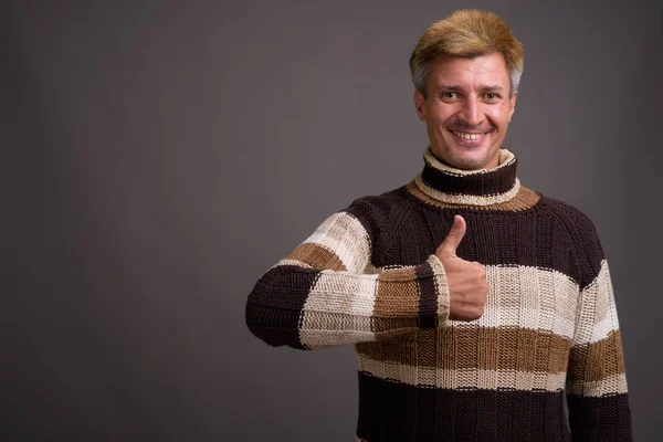 Homem com cabelo loiro vestindo camisola gola alta contra costas cinza — Fotografia de Stock