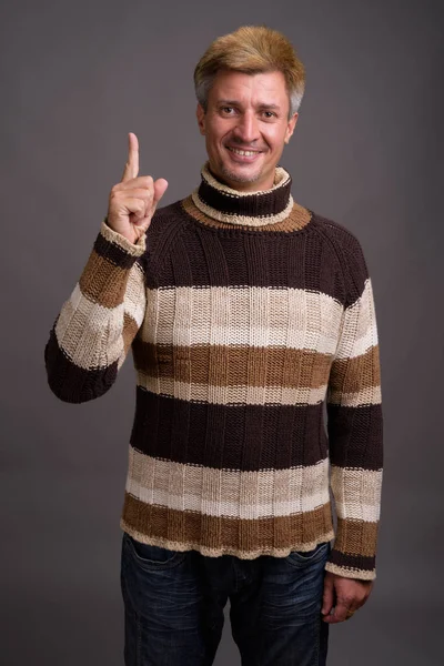 Bărbat cu păr blond purtând pulover cu gât turtleneck pe spate gri — Fotografie, imagine de stoc