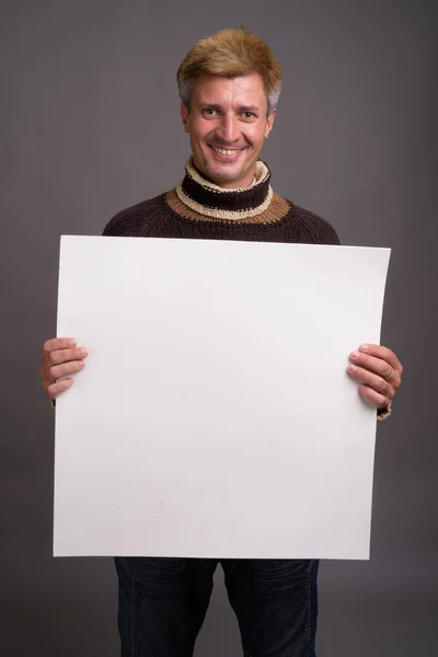 Άνθρωπος με ξανθά μαλλιά, φορώντας ζιβάγκο πουλόβερ εναντίον γκρι πίσω — Φωτογραφία Αρχείου
