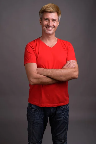 Uomo con i capelli biondi indossa camicia rossa contro sfondo grigio — Foto Stock