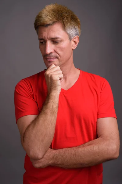Homem com cabelo loiro vestindo camisa vermelha contra fundo cinza — Fotografia de Stock