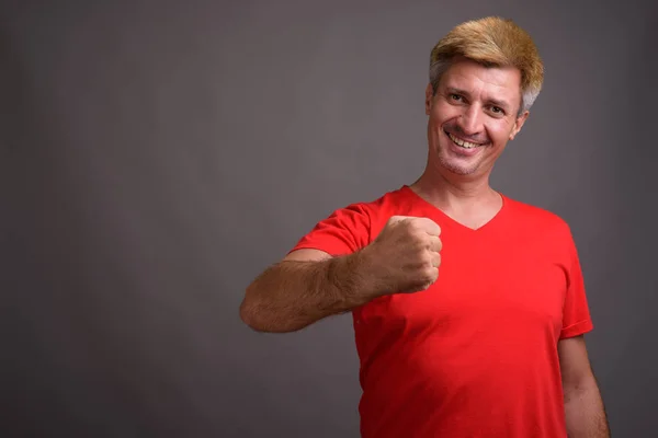 Uomo con i capelli biondi indossa camicia rossa contro sfondo grigio — Foto Stock