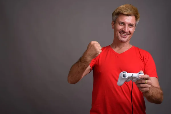 Man with blond hair wearing red shirt against gray background — Stock Photo, Image