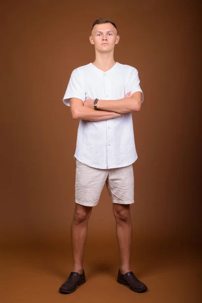 Hombre joven con camisa blanca sobre fondo marrón —  Fotos de Stock