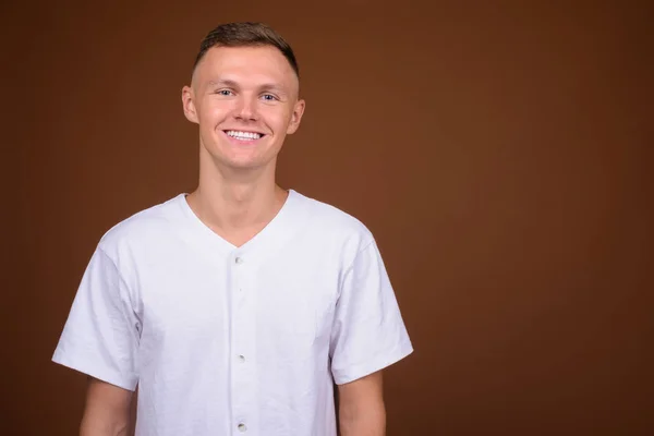 Giovane uomo che indossa camicia bianca contro sfondo marrone — Foto Stock