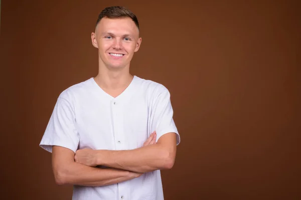 Jovem vestindo camisa branca contra fundo marrom — Fotografia de Stock