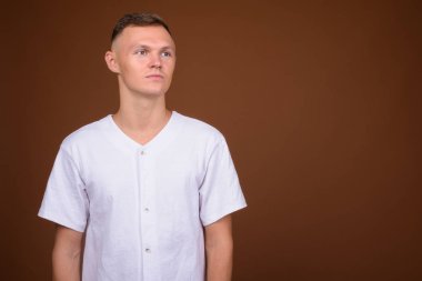 Kahverengi arka plan beyaz gömlek giymiş genç adam