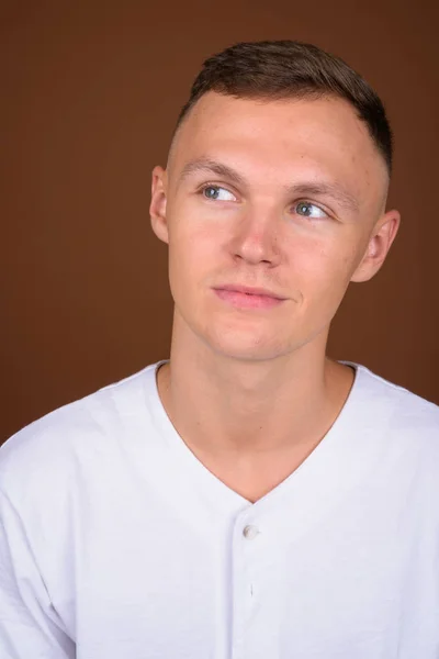 Young man wearing white shirt against brown background — Stock Photo, Image