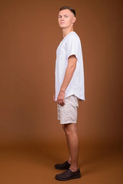 Jovem vestindo camisa branca contra fundo marrom — Fotografia de Stock