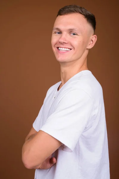 Young man wearing white shirt against brown background — Stock Photo, Image