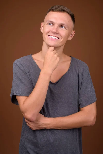 Hombre joven con camisa gris sobre fondo marrón — Foto de Stock